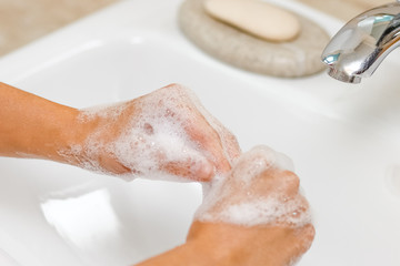 a Washing hands with soap under the faucet with water