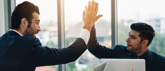 business background of two businessmen having high five together showing success and friendship in...