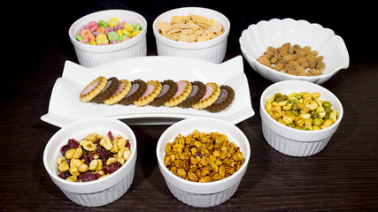 Variety of healthy food like peanuts, cereal, cookies and almonds. 