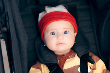 Cute Little Baby Wearing a Hat Seated in Stroller