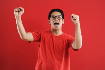 Fototapeta premium Young asian man happy and excited expressing winning gesture. Successful and celebrating