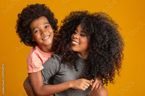 Portrait of young African American mother with toddler son. Yellow background. Brazilian family.