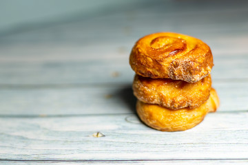 Stacked Homemade glazed puff pastry rolls on a  dark blue wooden background.  Shallow depth of field. Selective focusing