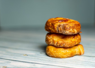 Stacked Homemade glazed puff pastry rolls on a  dark blue wooden background.  Shallow depth of field. Selective focusing