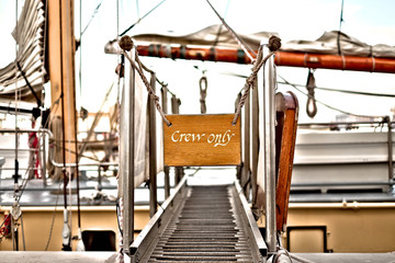 Gangway leading to a deck of a classic sailing ship, 'Crew only' sign marking entrance access for...