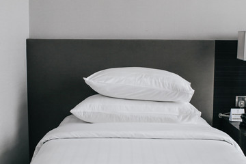 Fototapeta na wymiar Stacking of White pillows on a bed Comfortable soft pillows on the bed.Hotel room with freshly made bed, perfectly clean and ironed sheets, puffy pillows in natural sun light. Close up, copy space for