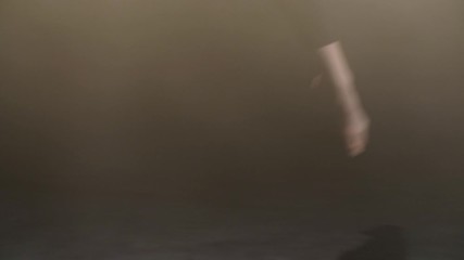 Close-up of female dancer bare feet showing confident choreographic steps of modern contemporary dance on black stage in smoky studio. Barefoot woman dancing gently against black background