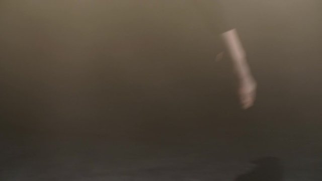 Close-up of female dancer bare feet showing confident choreographic steps of modern contemporary dance on black stage in smoky studio. Barefoot woman dancing gently against black background