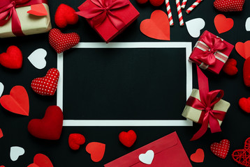 Table top view image of decoration valentine's day background concept.Flat lay arrangement of red shape & gift box with essential items on modern rustic black wood with middle space for mock up design