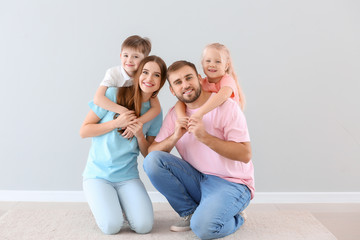 Portrait of happy family near light wall