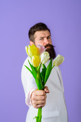 Bouquet of tulips. Bearded man holds bouquet of flowers. Handsome man with flowers. Businessman with bouquet tulips for birthday. Valentines or Womens Day. Serious man holds flowers. Selective focus.