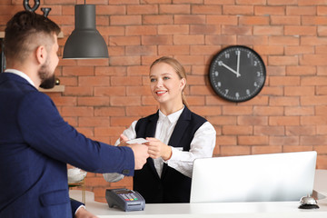 Young man paying for hotel room at reception