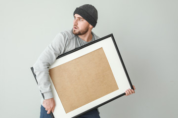 Thief with picture stolen from art gallery on light background