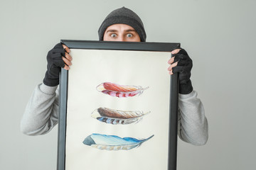 Thief with picture stolen from art gallery on light background