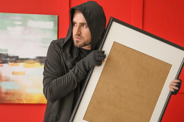 Thief stealing picture from art gallery