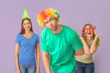 People in funny disguise on color background. April fools' day celebration