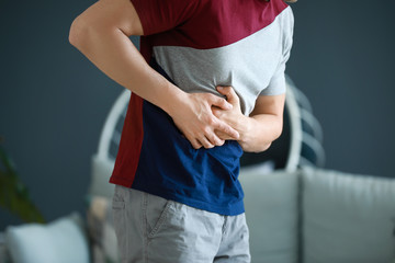 Young man suffering from abdominal pain at home