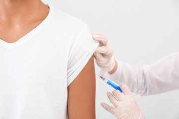 Doctor vaccinating teenage boy on white background, closeup