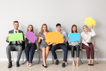 Group of business people with blank speech bubbles near light wall