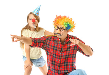Father and daughter in funny disguise and with party whistles on white background. April fools' day...