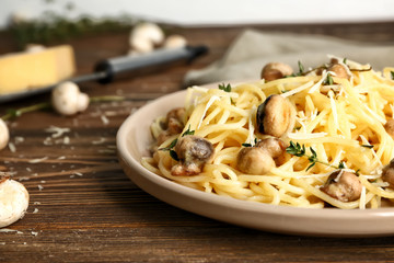 Plate with tasty pasta and mushrooms on wooden table, closeup