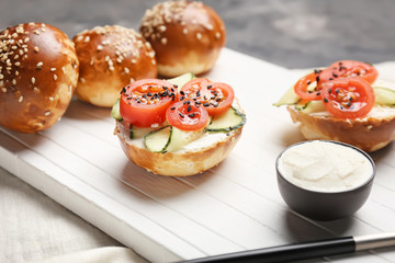 Fresh buns with tasty cream cheese and vegetables on table