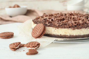 Tasty chocolate cheesecake with cookies on white table