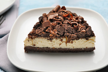 Plate with piece of tasty chocolate cheesecake on table