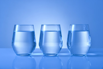 Glasses of fresh water on color background