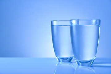 Glasses of fresh water on color background