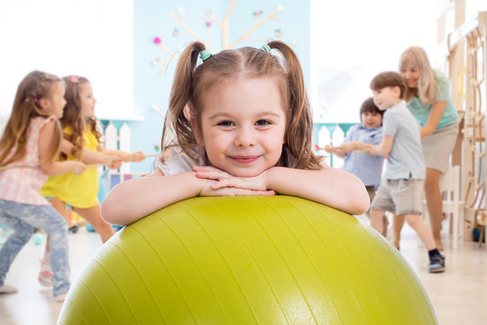 Children in the gym. Preschool kid girl with fitball in physical education lesson.
