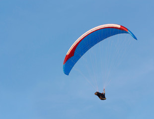 Paraglider is flying against the blue sky