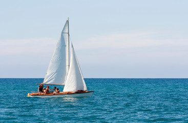 Fototapeta premium A sailboat with a group of people in life jackets is floating in the sea