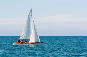 A sailboat with a group of people in life jackets is floating in the sea