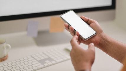 Cropped shot of male freelancer holding smartphone while sitting in  office room