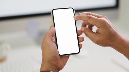 Close up view of male freelancer typing  smartphone while sitting in workspace