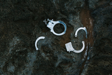 Pieces of broken handcuffs on black rock