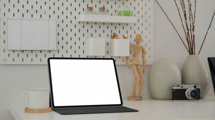 Cropped shot of modern designer workplace with mock up tablet , wooden figure, camera and decorations