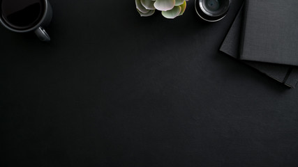 Overhead shot of dark modern workplace with copy space, camera lens, office supplies and decorations