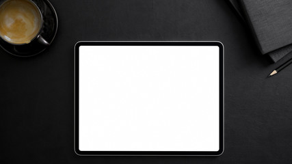 Top view of dark modern workplace with blank screen tablet, office supplies and coffee cup