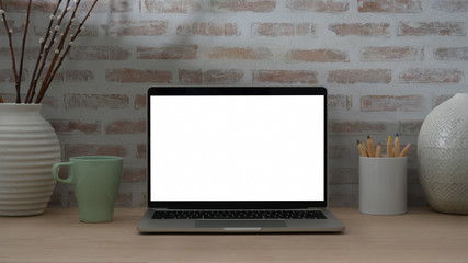 Cropped shot of contemporary designer workspace with blank screen laptop, coloured pencils and decorations