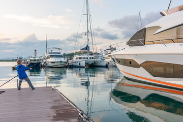 Fototapeta premium Boy Moor A Big Yacht On A Dock.
