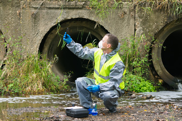 a man in a protective suit and mask photographs the area after a man-made accident on a mobile...