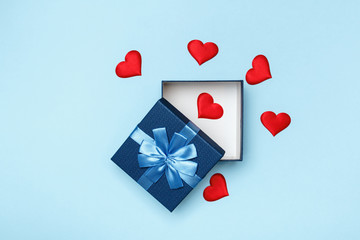 The concept of love and Valentine's Day. Open gift box and red hearts on a blue background