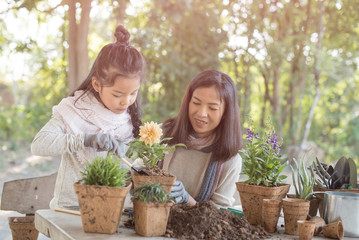 planting flowers. cute child girl helping her mother to care for plants. mom and her daughter...