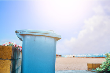 Trashcan on the beach. Blue waste bucket on the shore of the lake.