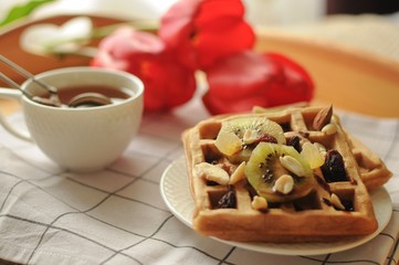 Morning in the bed with homemade Belgium waffles, black tea and tulip flowers