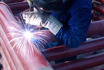 Workers are using welding machines to work on steel pipes for use in construction. Welding of structural pipes requires work skills. technician engineer build iron flame connect structure in workplace