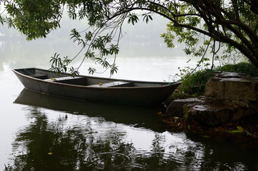 Naklejka na ściany i meble Steel boat in rain moored at Three Pools Mirroring the Moon Island West Lake Hangzhou China