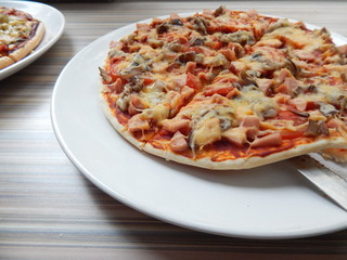 pizza with ham and mushrooms raised on a knife